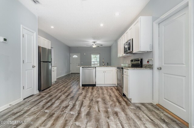 4725 Melanie St, Hastings, FL 32145 - kitchen with stainless steel appliances, light wood finished floors, white cabinetry, ceiling fan, and recessed lighting