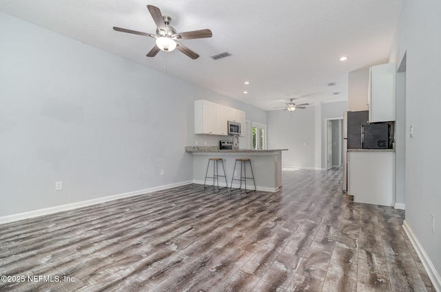4725 Melanie St, Hastings, FL 32145 - kitchen featuring stainless steel microwave, a ceiling fan, wood finished floors, white cabinetry, and recessed lighting