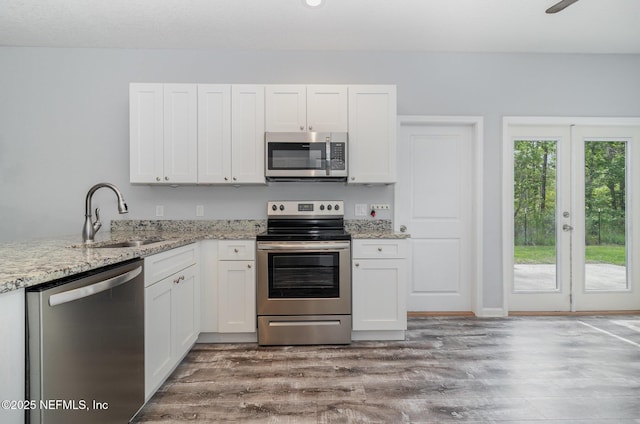 4725 Melanie St, Hastings, FL 32145 - kitchen featuring stainless steel appliances, white cabinetry, wood finished floors, and light stone countertops