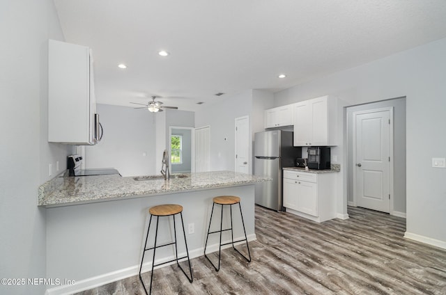 4725 Melanie St, Hastings, FL 32145 - kitchen with appliances with stainless steel finishes, a peninsula, wood finished floors, white cabinets, and ceiling fan