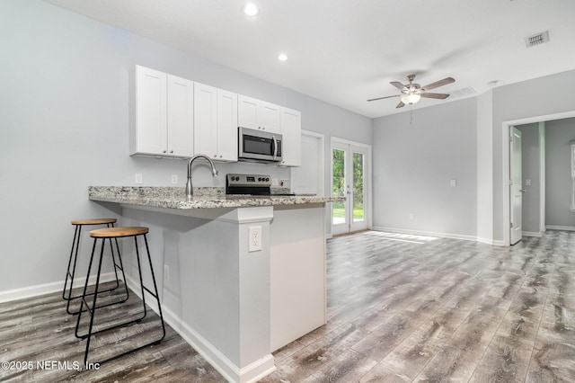 4725 Melanie St, Hastings, FL 32145 - kitchen with stainless steel microwave, a ceiling fan, light wood finished floors, white cabinetry, and recessed lighting