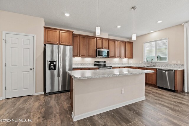 12206 Orange Grove Dr, Jacksonville, FL 32223 - kitchen featuring stainless steel appliances, brown cabinets, a kitchen island, dark wood-type flooring, and hanging light fixtures
