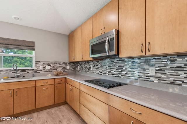 7250 Steventon Way, Jacksonville, FL 32244 - kitchen with stainless steel microwave, black electric cooktop, light wood finished floors, light countertops, and decorative backsplash