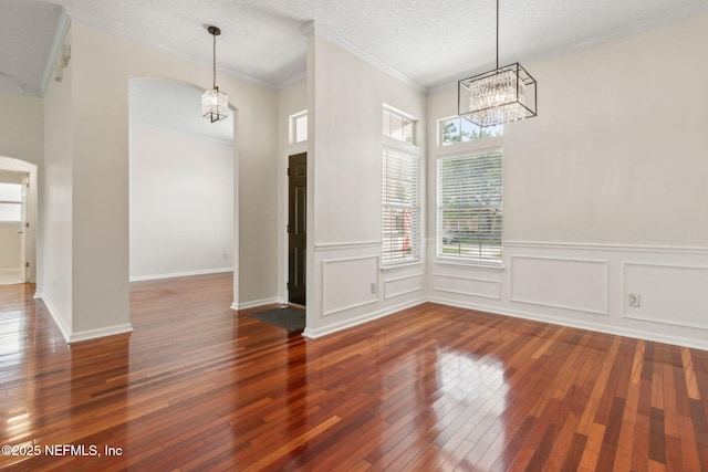1912 Bluebonnet Way, Fleming Island, FL 32003 - unfurnished dining area featuring a chandelier, hardwood / wood-style floors, arched walkways, ornamental molding, and wainscoting