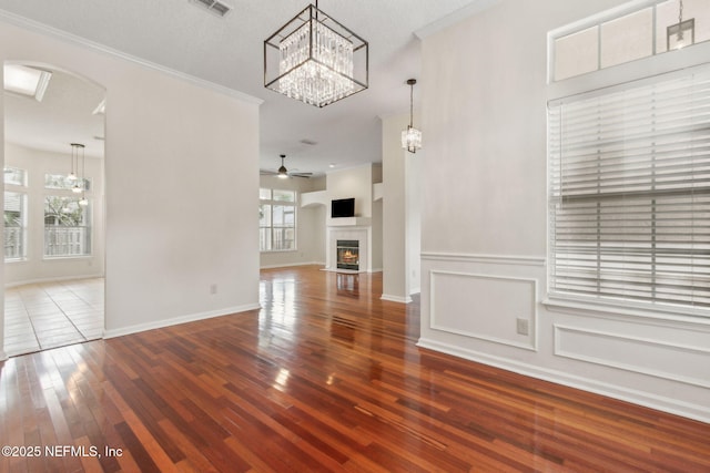1912 Bluebonnet Way, Fleming Island, FL 32003 - unfurnished living room with arched walkways, wood-type flooring, ceiling fan, a chandelier, and a fireplace with flush hearth