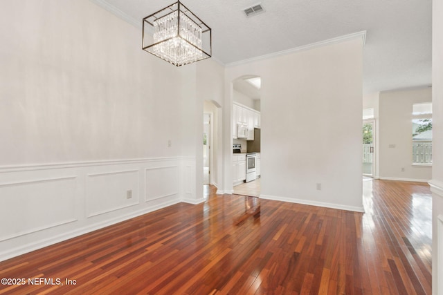 1912 Bluebonnet Way, Fleming Island, FL 32003 - unfurnished dining area featuring arched walkways, wood-type flooring, crown molding, a chandelier, and wainscoting