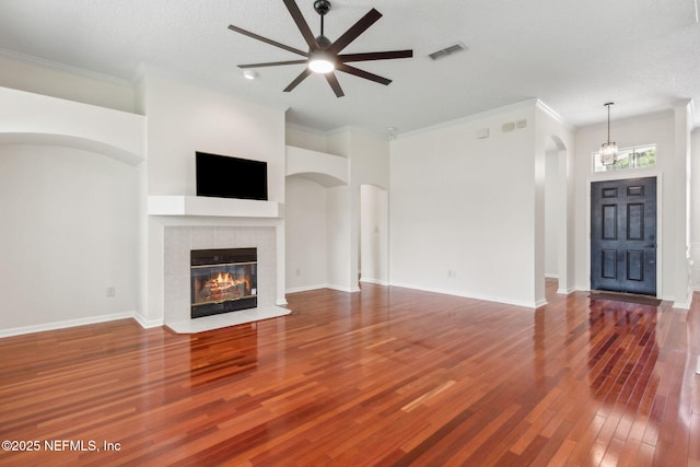 1912 Bluebonnet Way, Fleming Island, FL 32003 - unfurnished living room with a ceiling fan, wood finished floors, a tile fireplace, crown molding, and arched walkways