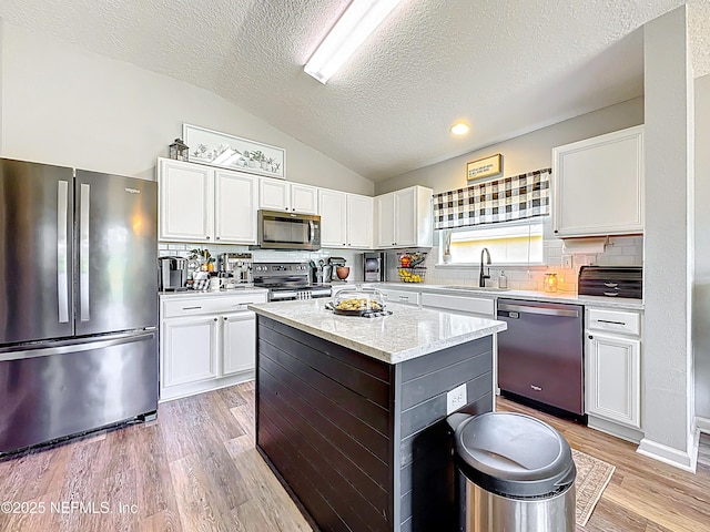 78151 Duckwood Trl, Yulee, FL 32097 - kitchen with stainless steel appliances, lofted ceiling, a textured ceiling, light wood-type flooring, and white cabinetry