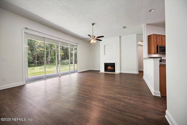 409 Spring Ridge Ct, Saint Augustine, FL 32092 - unfurnished living room featuring a ceiling fan, a textured ceiling, a fireplace with flush hearth, and dark wood-style flooring