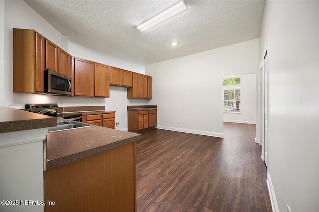 409 Spring Ridge Ct, Saint Augustine, FL 32092 - kitchen featuring appliances with stainless steel finishes, brown cabinets, dark wood-type flooring, a textured ceiling, and dark countertops