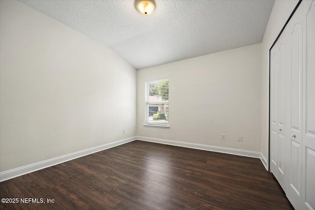 409 Spring Ridge Ct, Saint Augustine, FL 32092 - unfurnished bedroom with a closet, dark wood-style flooring, a textured ceiling, and lofted ceiling