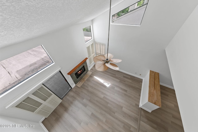511 Selva Lakes Cir, Atlantic Beach, FL 32233 - unfurnished living room featuring wood finished floors, a textured ceiling, a warm lit fireplace, and ceiling fan