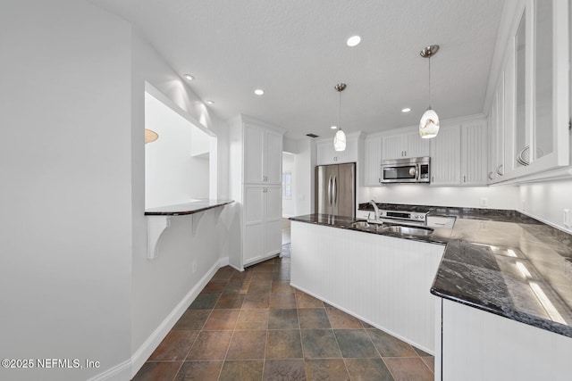 511 Selva Lakes Cir, Atlantic Beach, FL 32233 - kitchen featuring stainless steel appliances, white cabinets, a peninsula, dark stone finish floors, and hanging light fixtures