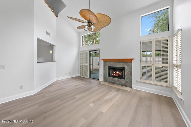 511 Selva Lakes Cir, Atlantic Beach, FL 32233 - unfurnished living room with a towering ceiling, a tile fireplace, ceiling fan, and wood finished floors