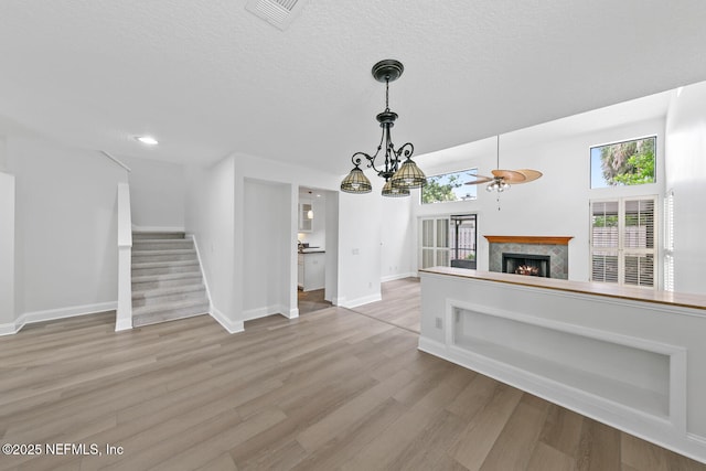 511 Selva Lakes Cir, Atlantic Beach, FL 32233 - unfurnished living room with a warm lit fireplace, healthy amount of natural light, wood finished floors, a ceiling fan, and a textured ceiling