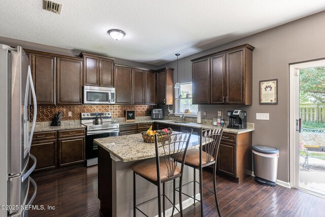 1341 River City St, Saint Augustine, FL 32092 - kitchen featuring appliances with stainless steel finishes, dark brown cabinetry, dark wood-style floors, a breakfast bar area, and a kitchen island