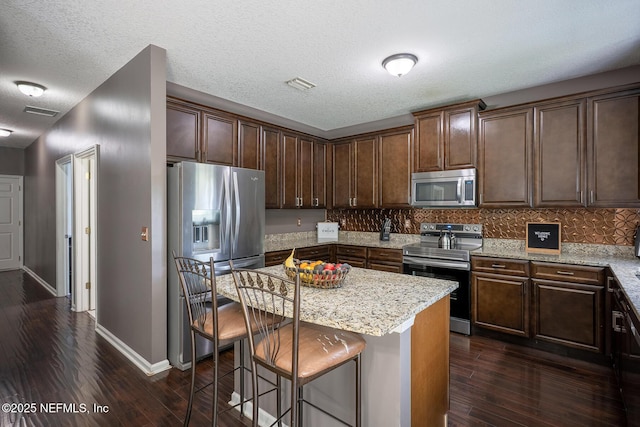 1341 River City St, Saint Augustine, FL 32092 - kitchen with appliances with stainless steel finishes, dark wood finished floors, a kitchen bar, backsplash, and a textured ceiling