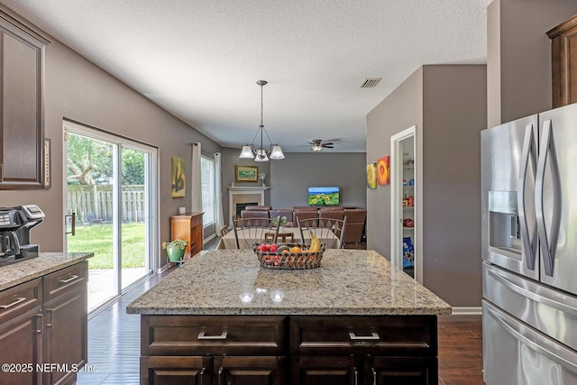 1341 River City St, Saint Augustine, FL 32092 - kitchen with stainless steel fridge, dark wood-style flooring, a fireplace, dark brown cabinets, and a textured ceiling