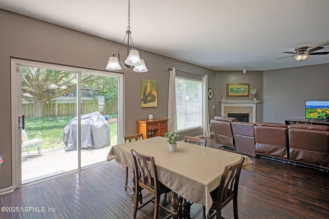 1341 River City St, Saint Augustine, FL 32092 - dining room with a tile fireplace, a chandelier, dark wood-style flooring, a textured ceiling, and a ceiling fan
