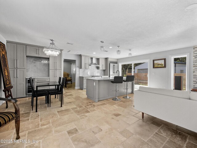 5062 N Ocean Shore Blvd, Palm Coast, FL 32137 - kitchen with gray cabinets, stone tile floors, wall chimney range hood, recessed lighting, and a kitchen breakfast bar