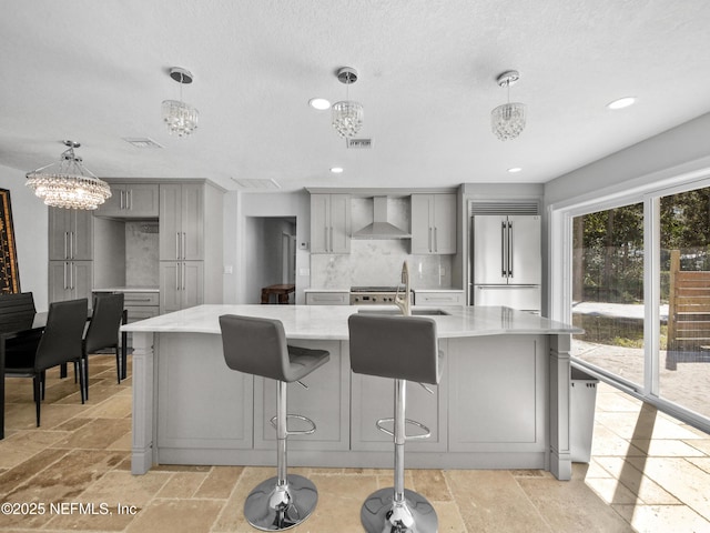 5062 N Ocean Shore Blvd, Palm Coast, FL 32137 - kitchen featuring high end refrigerator, gray cabinetry, wall chimney range hood, stone tile floors, and a chandelier