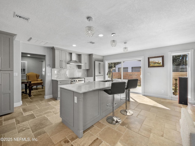 5062 N Ocean Shore Blvd, Palm Coast, FL 32137 - kitchen with gray cabinetry, wall chimney range hood, high quality appliances, light countertops, and a textured ceiling