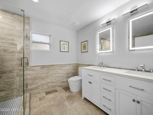5062 N Ocean Shore Blvd, Palm Coast, FL 32137 - full bathroom featuring tile walls, double vanity, a stall shower, a wainscoted wall, and stone finish floors