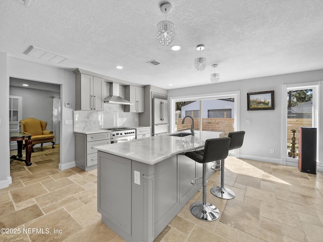 5062 N Ocean Shore Blvd, Palm Coast, FL 32137 - kitchen featuring gray cabinets, wall chimney exhaust hood, premium appliances, stone tile flooring, and an island with sink