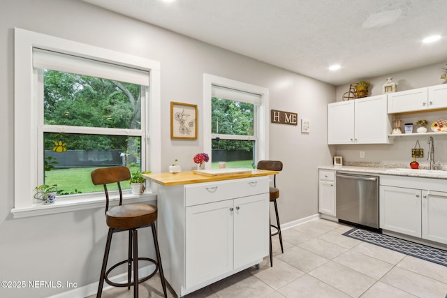 86759 Hester Dr, Yulee, FL 32097 - kitchen featuring stainless steel dishwasher, a breakfast bar area, white cabinets, open shelves, and light tile patterned floors