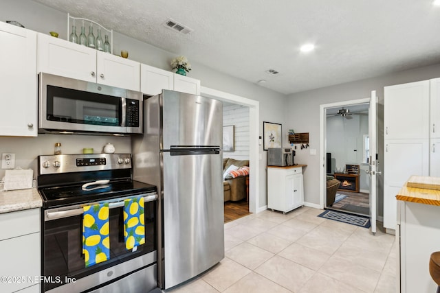 86759 Hester Dr, Yulee, FL 32097 - kitchen featuring appliances with stainless steel finishes, ceiling fan, white cabinetry, and light tile patterned flooring