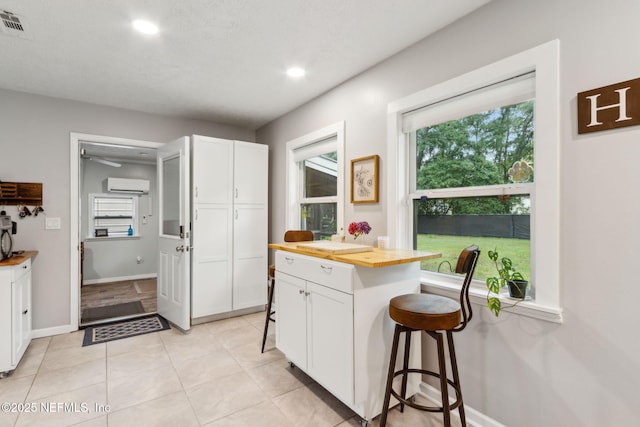 86759 Hester Dr, Yulee, FL 32097 - kitchen with wood counters, a wall mounted AC, white cabinets, a kitchen breakfast bar, and recessed lighting