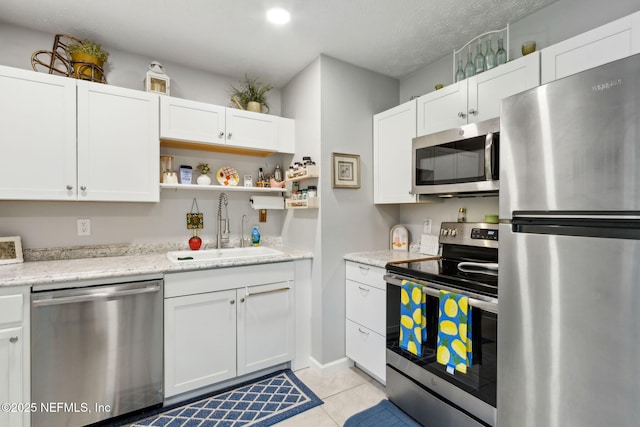 86759 Hester Dr, Yulee, FL 32097 - kitchen featuring appliances with stainless steel finishes, white cabinets, open shelves, light tile patterned floors, and light stone counters