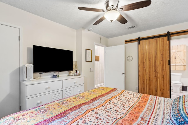 86759 Hester Dr, Yulee, FL 32097 - bedroom featuring a textured ceiling, a barn door, connected bathroom, and ceiling fan