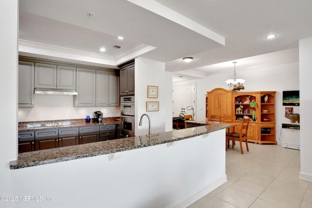 14402 Marina San Pablo Pl Unit 203, Jacksonville, FL 32224 - kitchen with a chandelier, crown molding, stainless steel double oven, dark stone counters, and a breakfast bar