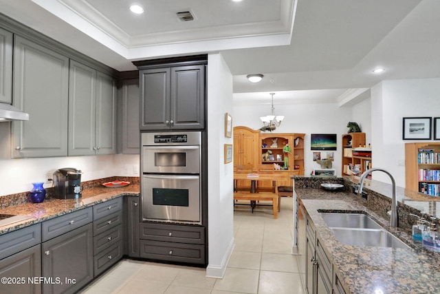 14402 Marina San Pablo Pl Unit 203, Jacksonville, FL 32224 - kitchen featuring double oven, a tray ceiling, a chandelier, gray cabinetry, and ornamental molding