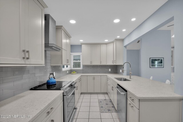 107 Hammock Cir, Saint Augustine, FL 32084 - kitchen with appliances with stainless steel finishes, wall chimney exhaust hood, a peninsula, light tile patterned floors, and backsplash