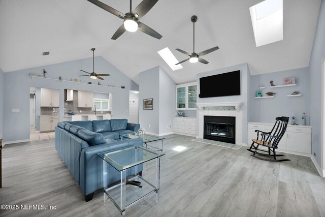 107 Hammock Cir, Saint Augustine, FL 32084 - living area with a skylight, a ceiling fan, high vaulted ceiling, light wood finished floors, and a tiled fireplace