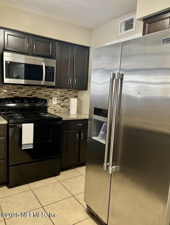1713 El Camino Rd Unit 3, Jacksonville, FL 32216 - kitchen with stainless steel appliances, backsplash, light tile patterned flooring, and light stone countertops