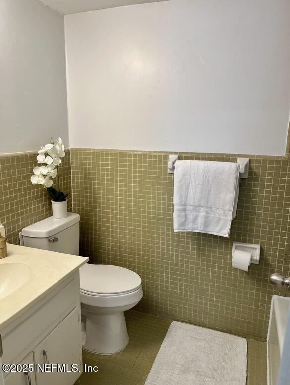 1713 El Camino Rd Unit 3, Jacksonville, FL 32216 - bathroom with a wainscoted wall, tile walls, vanity, a tub to relax in, and tile patterned floors