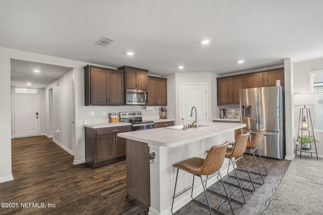 4433 Warm Springs Way, Middleburg, FL 32068 - kitchen featuring appliances with stainless steel finishes, light countertops, dark wood-type flooring, recessed lighting, and a breakfast bar area