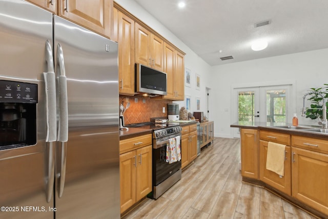 13967 Devan Lee Dr N, Jacksonville, FL 32226 - kitchen with appliances with stainless steel finishes, dark countertops, french doors, light wood finished floors, and tasteful backsplash