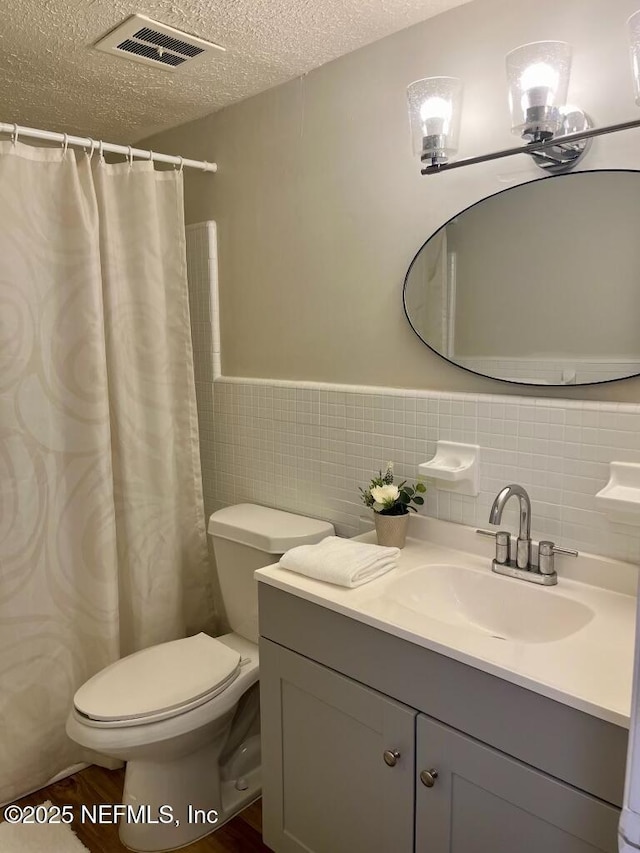 1716 El Camino Rd Unit 3, Jacksonville, FL 32216 - bathroom with vanity, a textured ceiling, tile walls, a wainscoted wall, and a shower with shower curtain