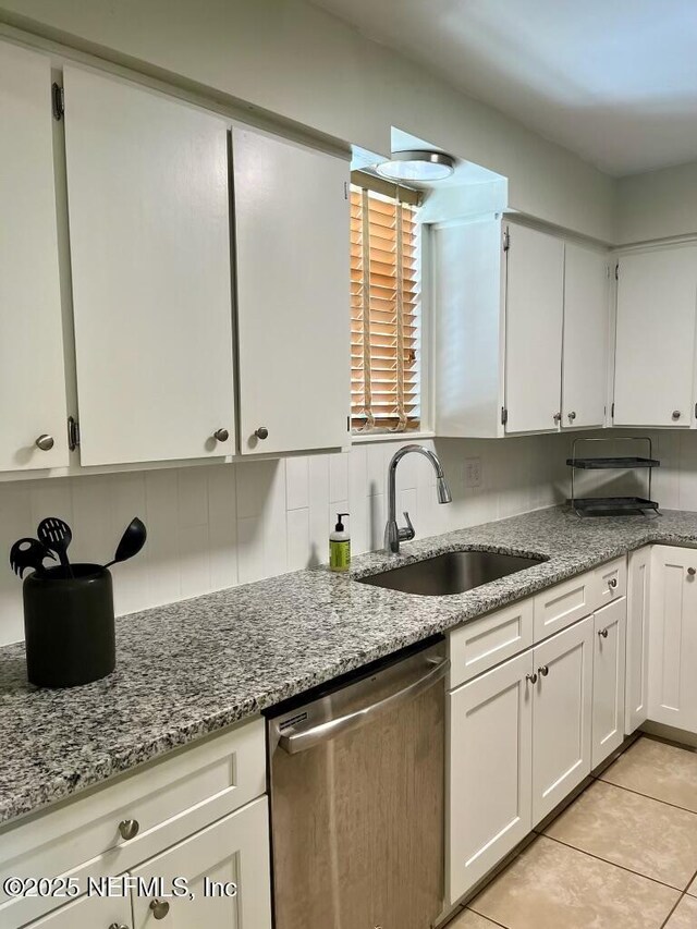 1716 El Camino Rd Unit 3, Jacksonville, FL 32216 - kitchen featuring stainless steel dishwasher, white cabinetry, light stone counters, decorative backsplash, and light tile patterned floors