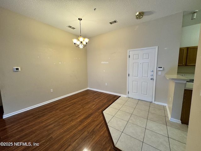 9626 Belda Way Unit 7, Jacksonville, FL 32257 - unfurnished dining area featuring a chandelier, light wood-style floors, and a textured ceiling