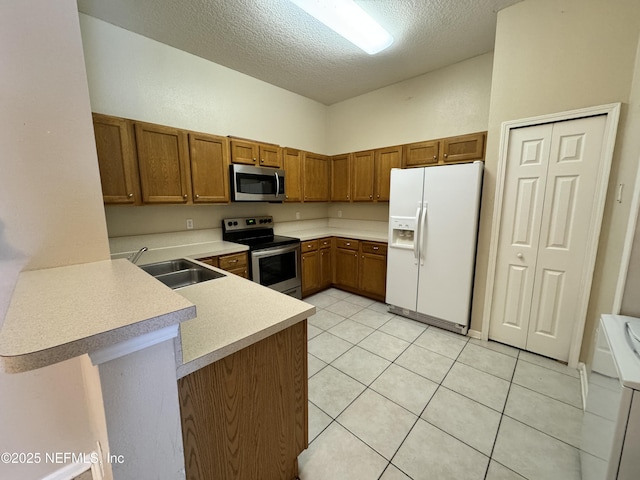 9626 Belda Way Unit 7, Jacksonville, FL 32257 - kitchen featuring appliances with stainless steel finishes, a textured ceiling, brown cabinets, light countertops, and a peninsula