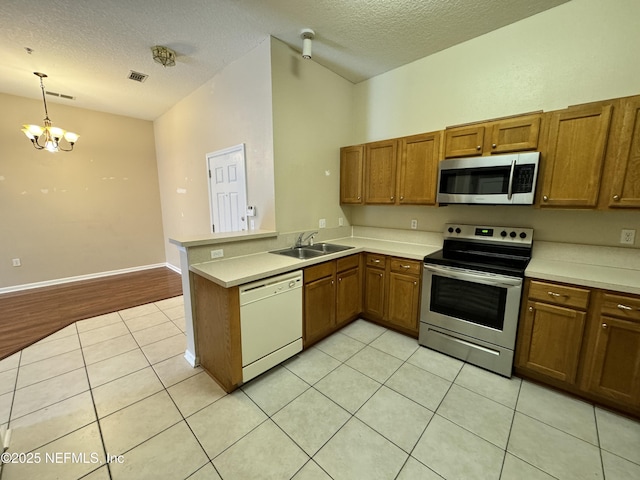 9626 Belda Way Unit 7, Jacksonville, FL 32257 - kitchen featuring stainless steel appliances, brown cabinets, a peninsula, a textured ceiling, and light tile patterned flooring