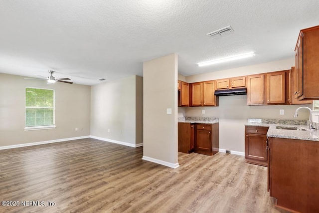5522 Paris Ave, Jacksonville, FL 32209 - kitchen with ceiling fan, light wood-style floors, brown cabinets, light stone counters, and open floor plan