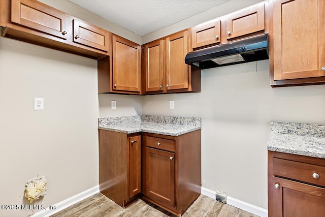 5522 Paris Ave, Jacksonville, FL 32209 - kitchen featuring under cabinet range hood, light wood-style flooring, light stone countertops, and brown cabinetry