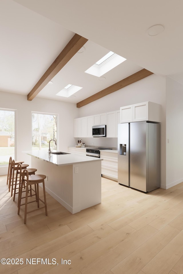 30 Bermuda Run Way, Saint Augustine Beach, FL 32080 - kitchen featuring appliances with stainless steel finishes, a skylight, white cabinetry, light wood-style floors, and a kitchen bar