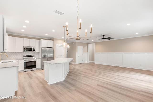6334 Salado Rd, Saint Augustine, FL 32080 - kitchen with appliances with stainless steel finishes, crown molding, a kitchen island, tasteful backsplash, and white cabinets